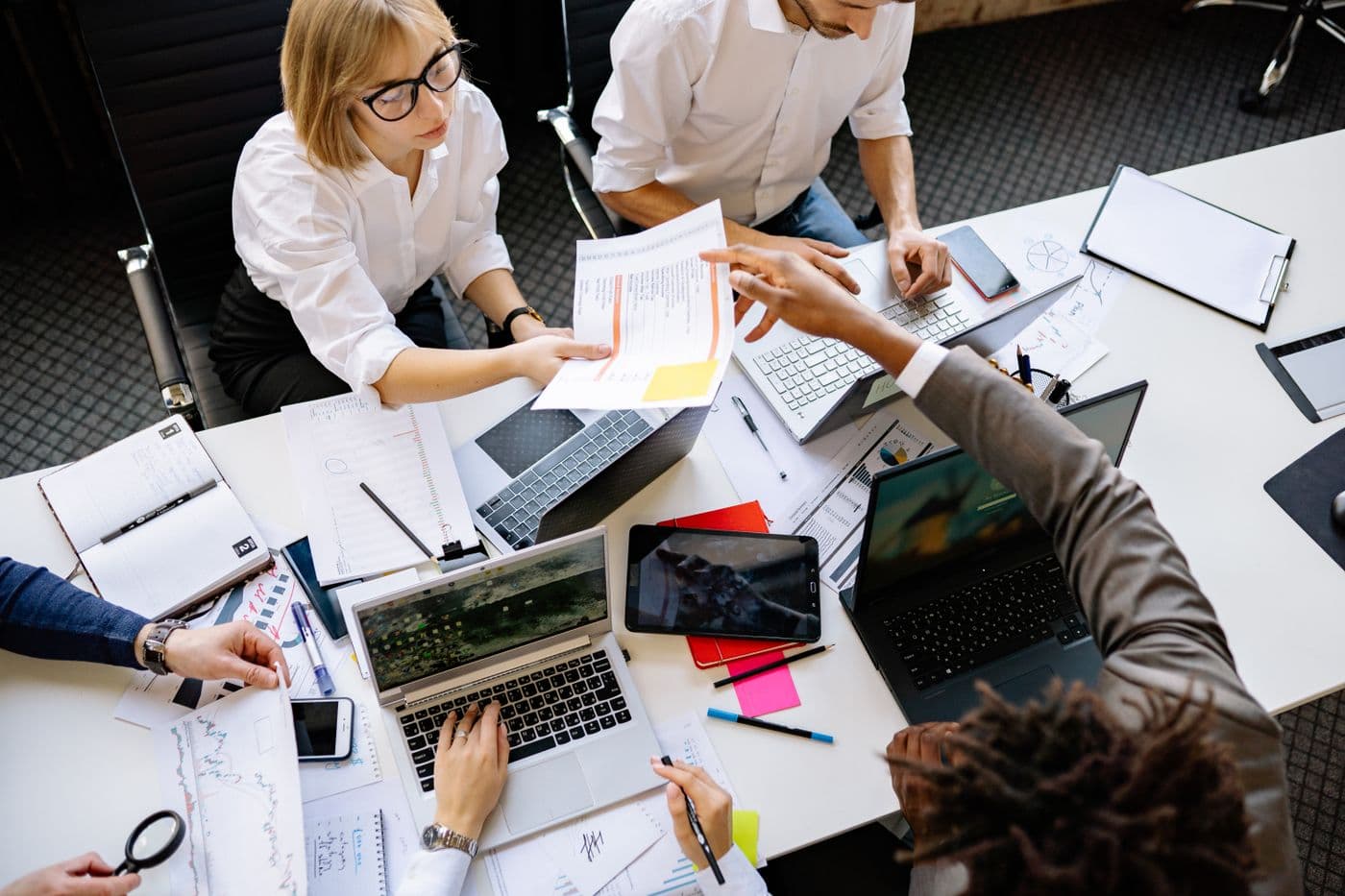 Vue de dessus d'une table de travail couverte de dossiers, de relevés et d'ordinateurs